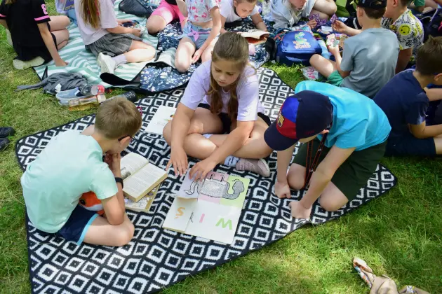 Przedszkolaki i uczniowie z książką pod chmurką w Parku Michalskiego